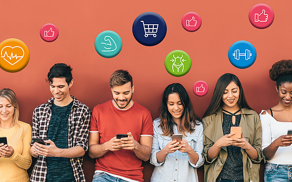 Sechs junge Erwachsene stehen vor einer orangefarbenen Wand, lächeln und schauen auf ihre Smartphones. Über ihren Köpfen schweben bunte Symbole für Gesundheit, Fitness, Shopping und soziale Medien.